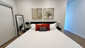 A bedroom with a large bed, a nightstand, a lamp, two wall art pieces, and a mirror. - Like a hotel but better! Pet friendly, exclusive patio, near beach, free parking (San Diego)