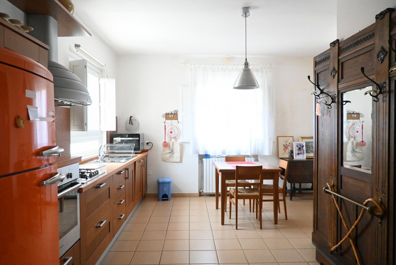 Una cocina con estufa, horno y comedor con sillas y mesa.