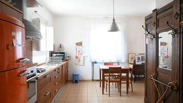 Una cocina con estufa, horno y comedor con sillas y mesa.