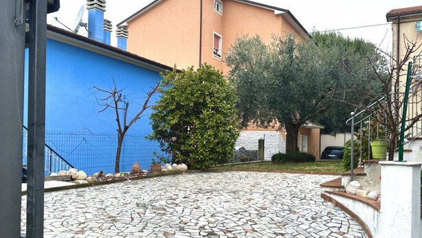 A courtyard with a stone floor, a blue wall, and a building with a beige facade. - S327 - Sirolo, comfortable two-room apartment well equipped (Sirolo)