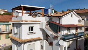 A multi-story residential building with balconies, satellite dishes, and a clear blue sky. - S327 - Sirolo, comfortable two-room apartment well equipped (Sirolo)