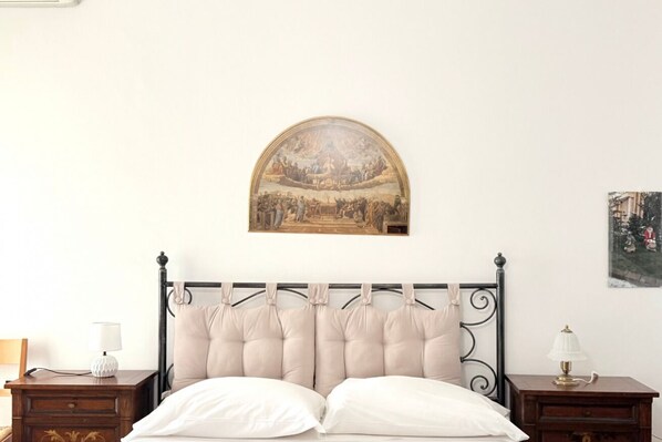Un dormitorio con cama, dos mesitas de noche, un cuadro colgado en la pared y una lámpara de mesa pequeña.