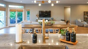 Une cuisine moderne dotée d’un plan de travail en marbre, d’un îlot central et d’un coin repas avec une grande table et des chaises.