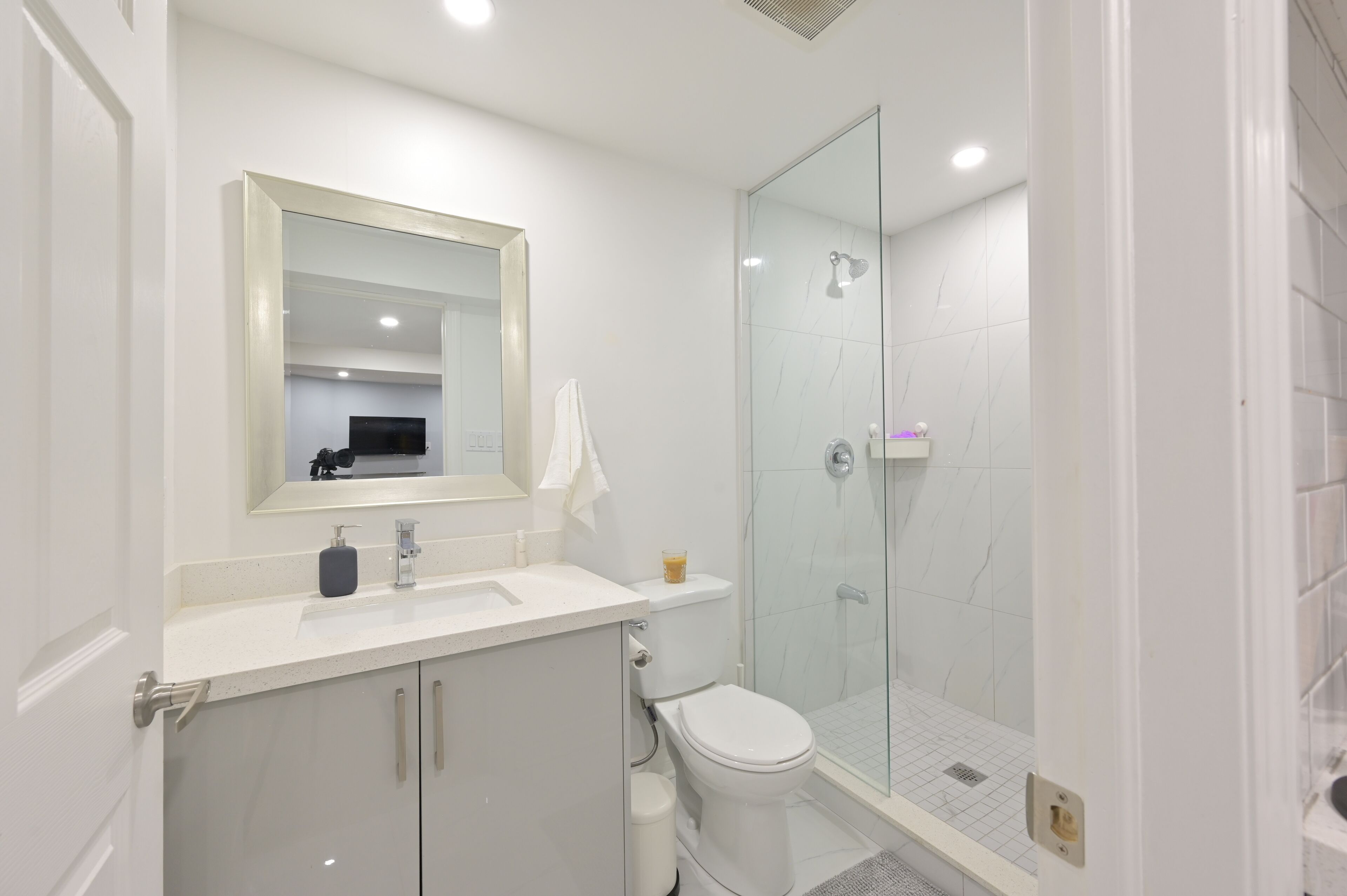 Une salle de bain moderne avec une douche à parois de verre, un lavabo blanc et des toilettes.