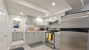 Una cocina moderna con electrodomésticos de acero inoxidable, armarios blancos y salpicadero de azulejos grises.