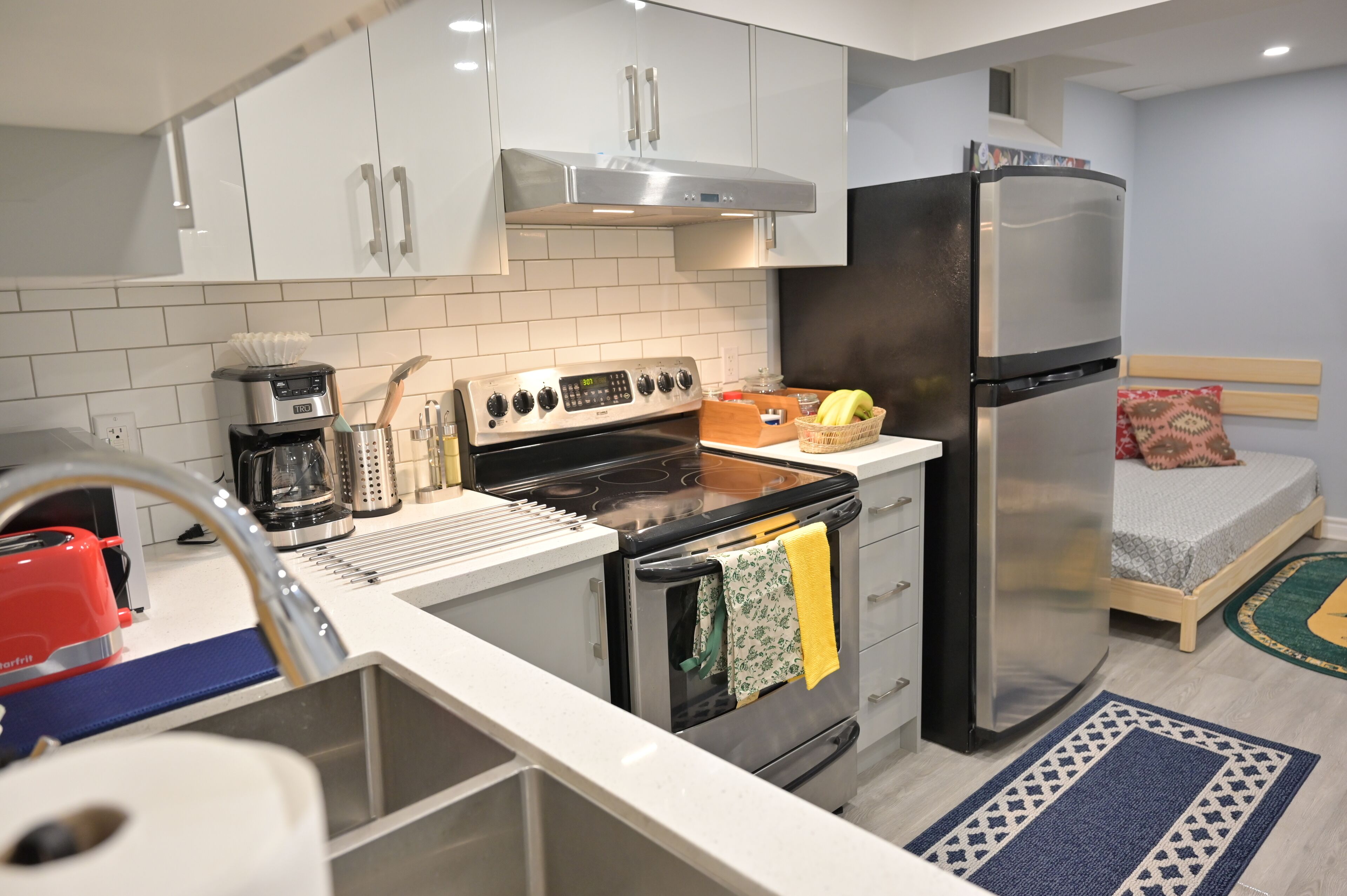 Una cocina compacta con armarios blancos, estufa de acero inoxidable y refrigerador.