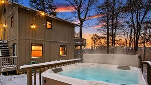 A wooden house with a hot tub and a deck.