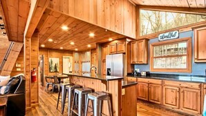 A wooden cabin interior with a kitchen, bar stools, and a 'Thankful' sign.
