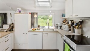 A compact kitchen with white cabinets, a Bosch dishwasher, a stove, and a window with curtains. - 3 bedroom beautiful home in Væggerløse (Væggerløse)