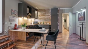 A modern kitchen with a wooden island, black chairs, and a dining table. - Ferienwohnung in Luxusvilla (Bahrdorf)