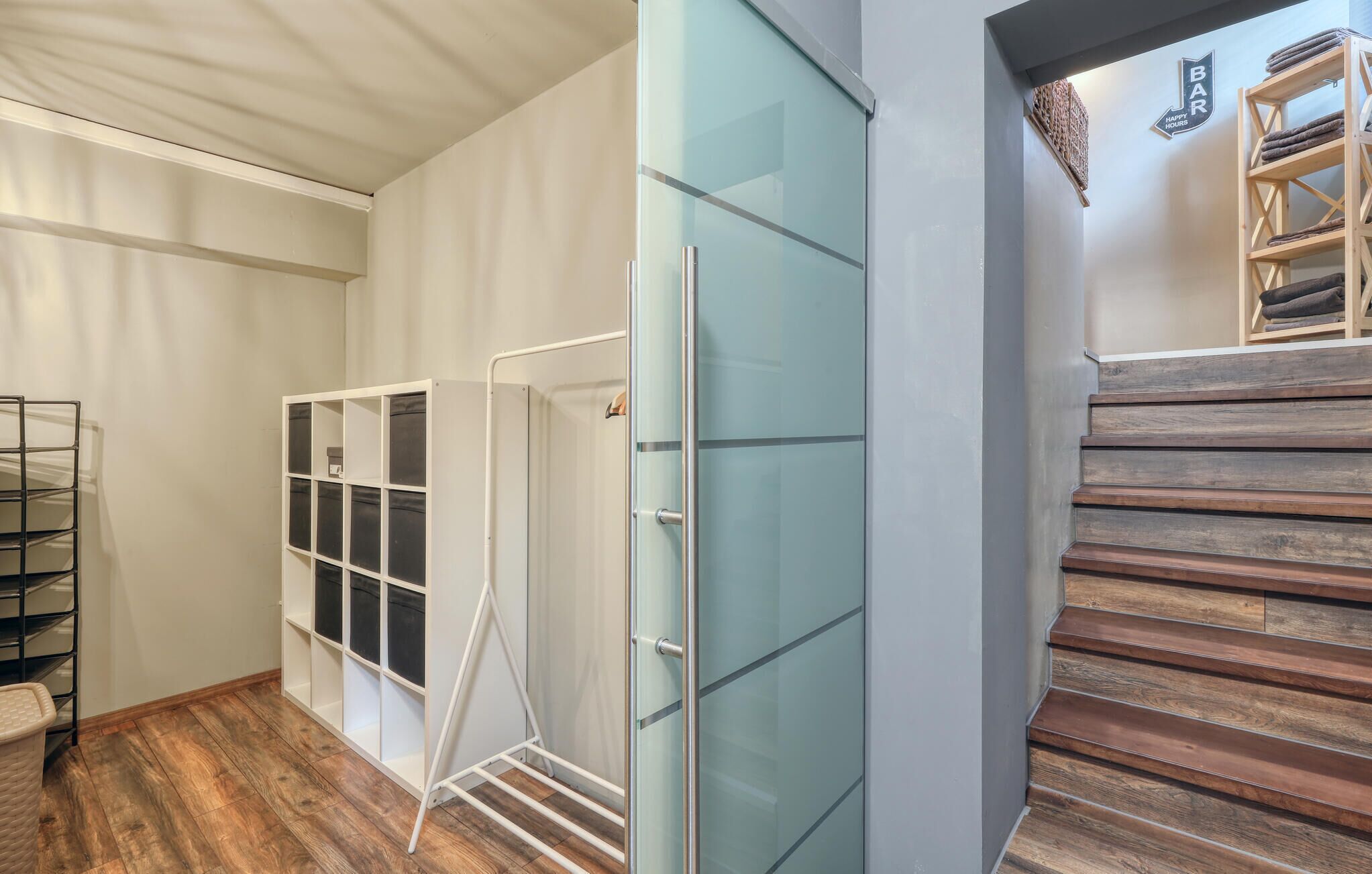 Um interior moderno com um armário de porta de vidro, um varal de metal e uma escada de madeira.