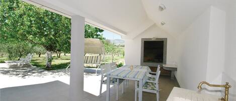 A patio with a table and chairs, a TV, and a sink.