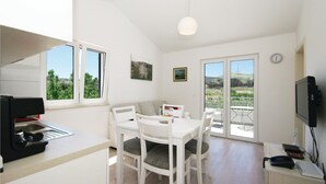 Eine moderne Küche mit Essbereich, Fernseher und Blick ins Freie.