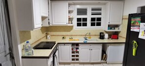 Kitchen features a sink, coffee maker, toaster, and refrigerator with a shelf above the sink.