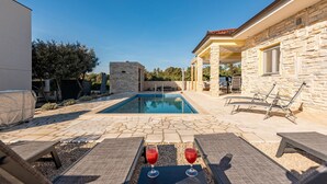 A pool area with lounge chairs and a stone building.