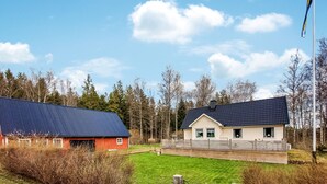 Une propriété rurale comprenant une grande grange, une maison avec un toit en pente et une cour clôturée.