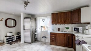Une cuisine de taille réduite équipée d’un réfrigérateur, d’un four à micro-ondes et de meubles de rangement en bois.