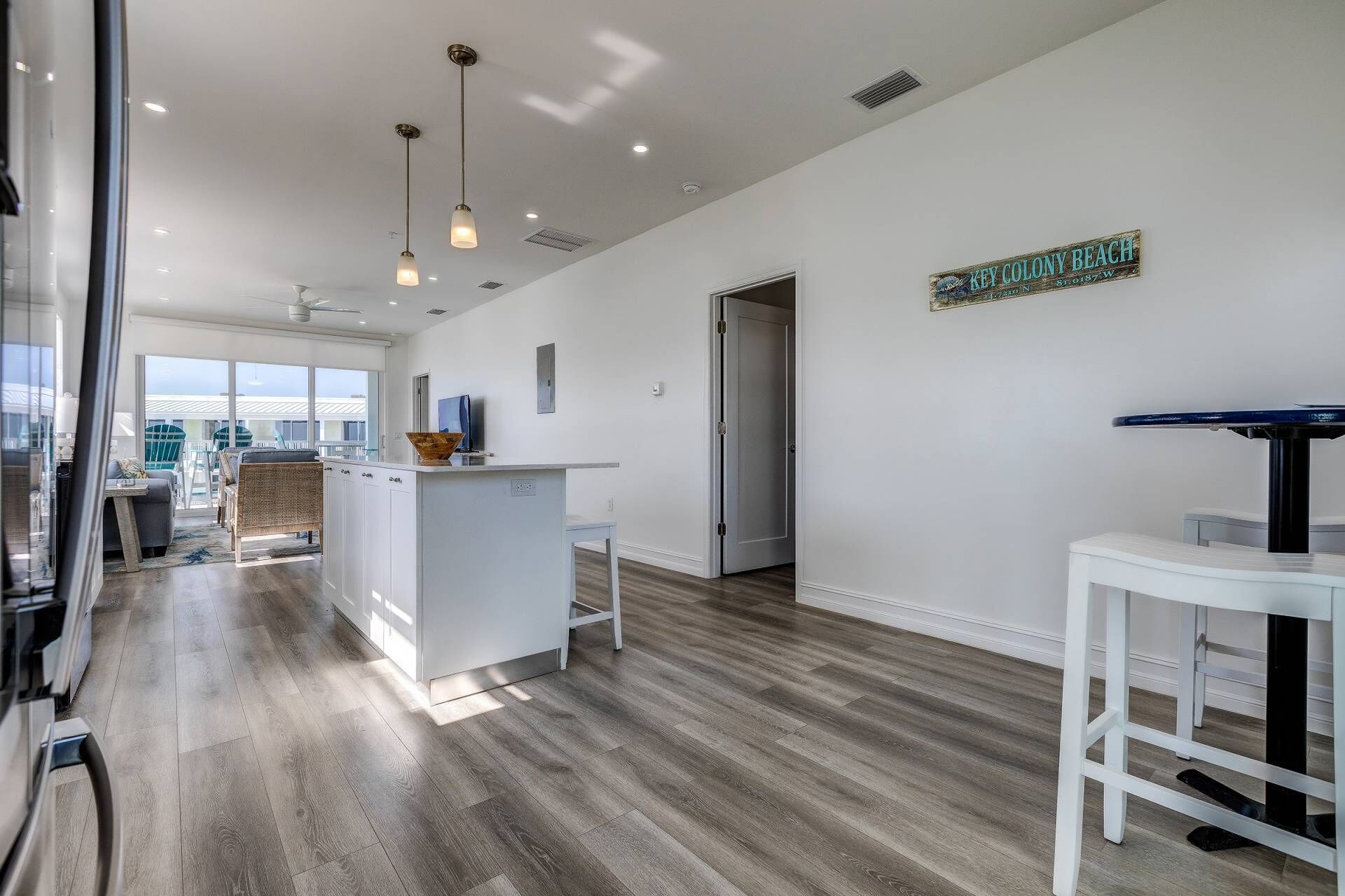 A modern kitchen with a central island, pendant lighting, and a view of Key Colony Beach.