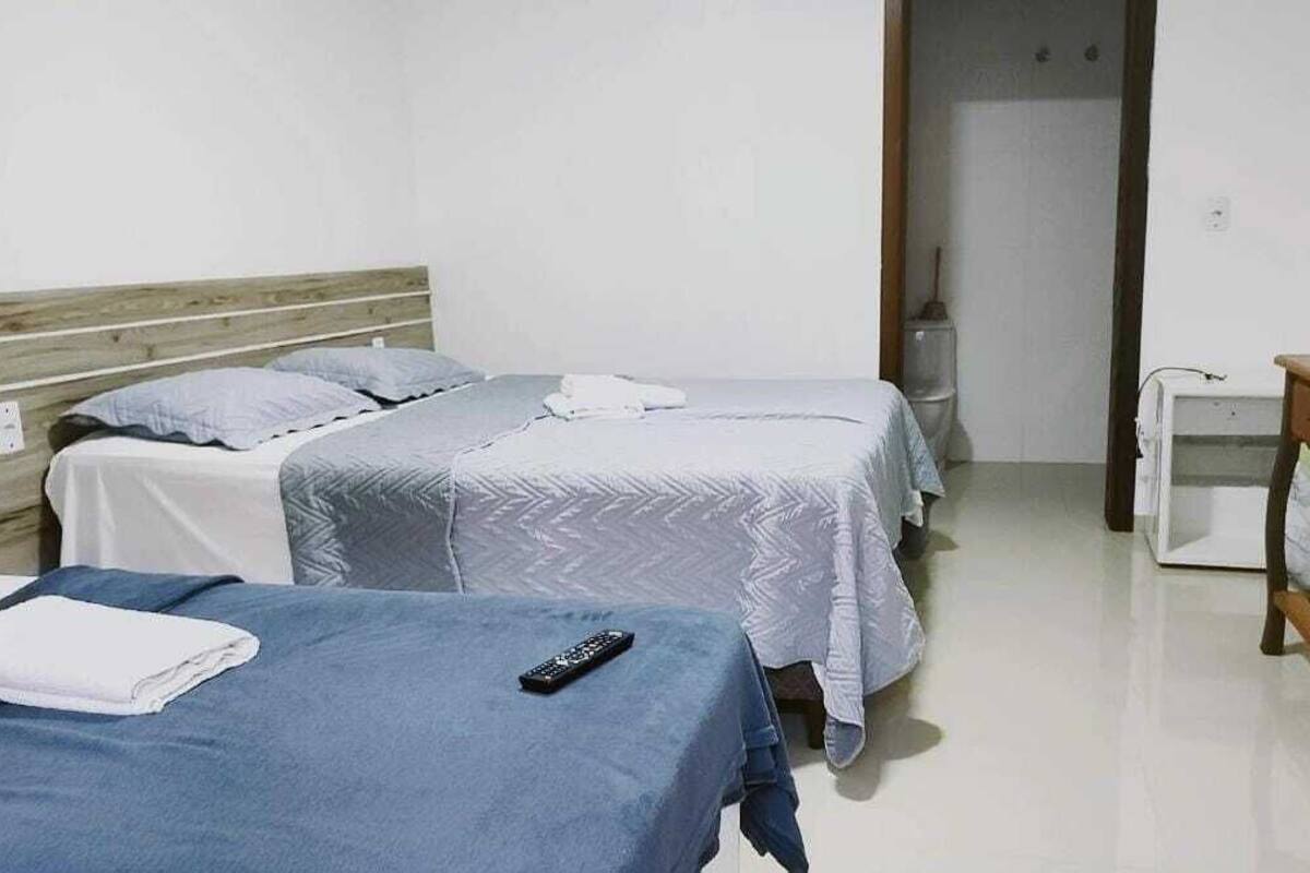 Ein Hotelzimmer mit zwei Einzelbetten, einem Holzkopfstück, einem kleinen Nachttisch und einer weißen Wand.