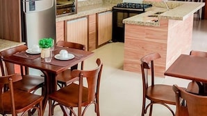 Uma cozinha moderna com armários de madeira, forno embutido e uma área de refeições com cadeiras e mesa de madeira.