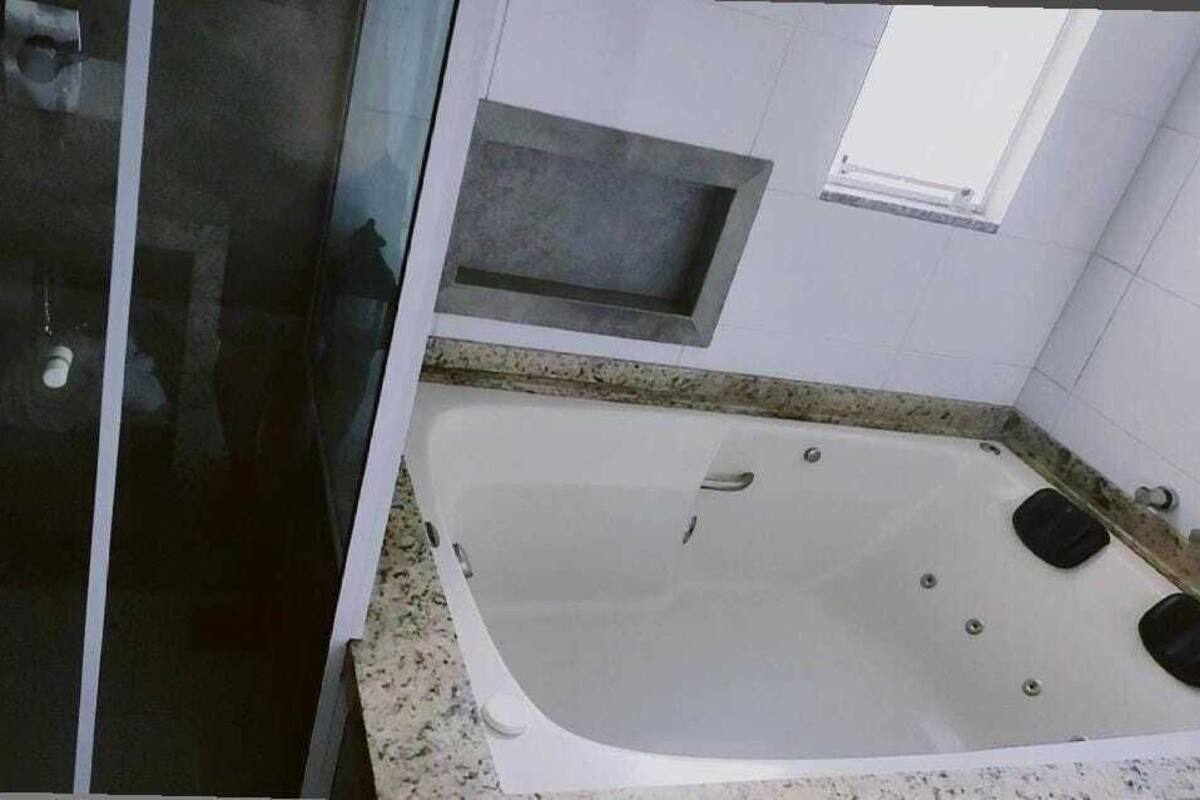 Ein Badezimmer mit Duschkabine aus Glas, einer Badewanne und einem kleinen Fenster.