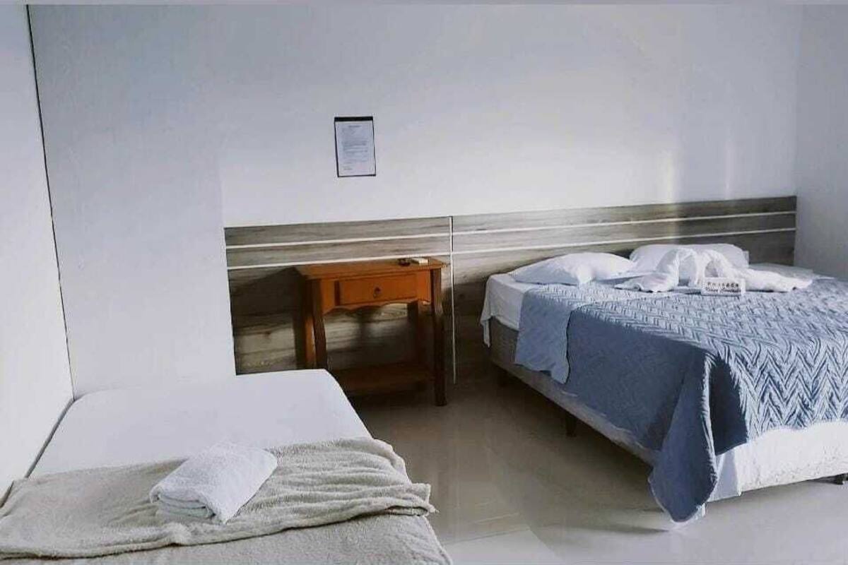 Ein Hotelzimmer mit zwei Betten, einem Holznachttisch und einer weißen Wand mit einem gerahmten Hinweis.