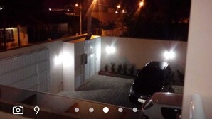 Vista noturna de uma área de estacionamento com um carro e um edifício ao fundo.