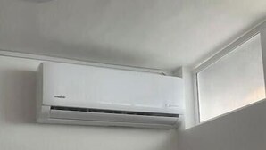 A bathroom with a white air conditioning unit, a circular mirror, and a decorative panel with cut-out shapes. - Cozy apartment in Laureles cool with Air/Acond. (Medellín)