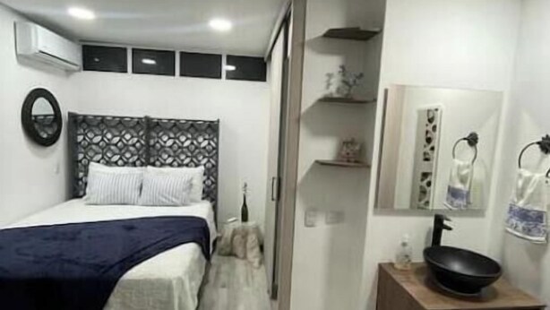 A modern bedroom with a bed, bedside table, and a built-in wardrobe. - Cozy apartment in Laureles cool with Air/Acond. (Medellín)