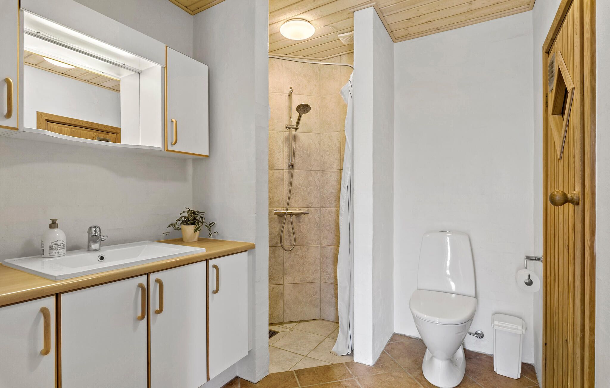 A bathroom with a white sink, a toilet, and a shower area.