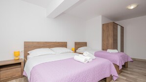 Hotellihuone, jossa on kaksi sänkyä, puiset päätyosat ja puinen vaatekaappi.