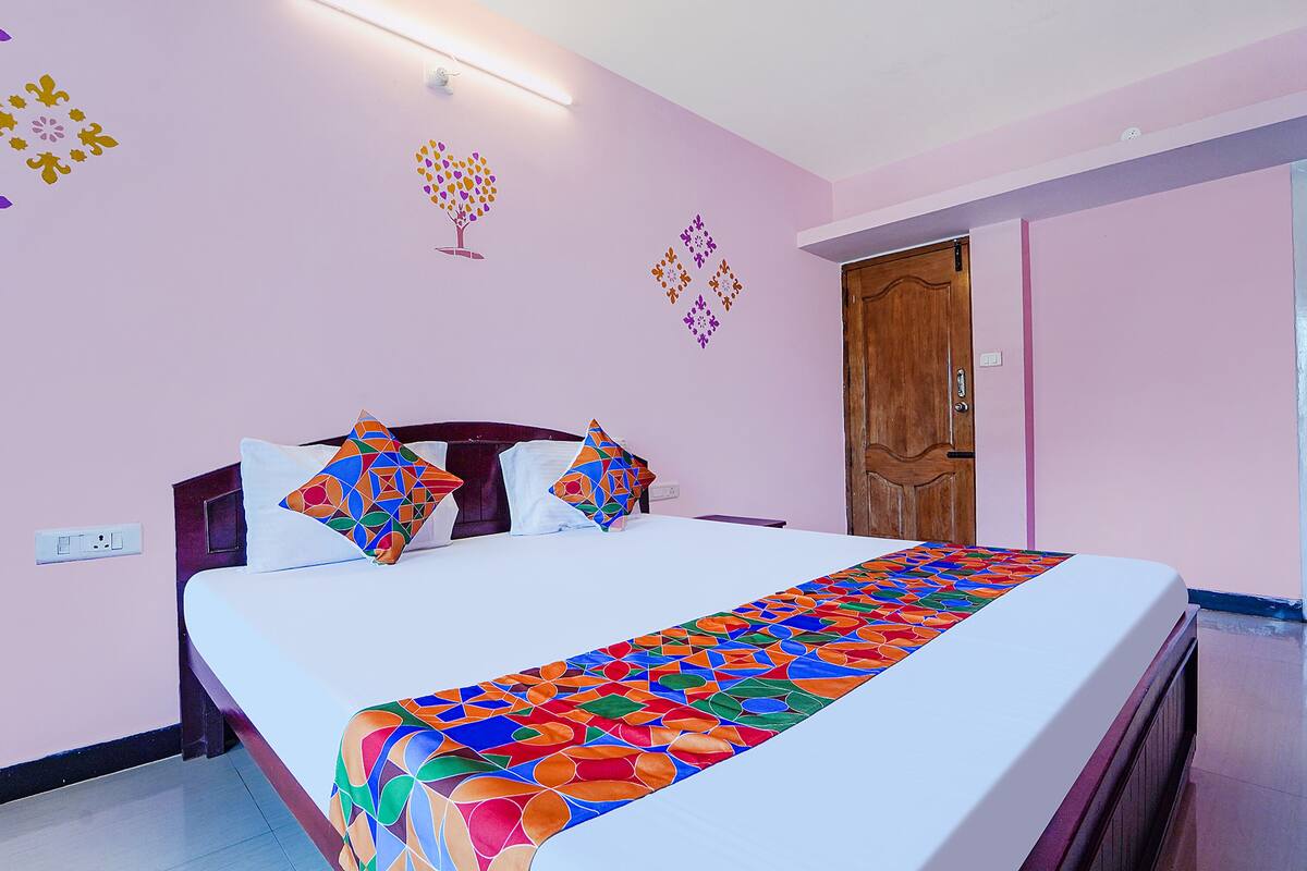 A neatly made bed with a colorful bedspread, a wooden headboard, and decorative wall art.