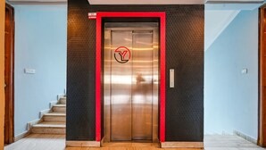 An elevator with a logo, a staircase, and a textured wall. - Fabexpress 24 Plus (Bengaluru)