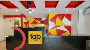 A reception desk with a bold logo, geometric wall art, and a potted plant. - Fabexpress 24 Plus (Bengaluru)