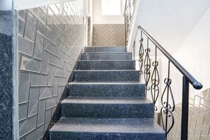 A staircase with black marble steps and metal railings, leading to a room with a tiled wall. - Fabexpress Kirtiraj (Panvel)