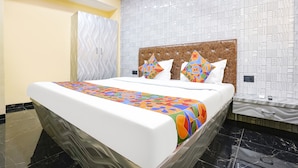 Un letto rifatto con cura, con una coperta dai colori vivaci e fantasia geometrica, una testiera imbottita e cuscini decorativi.