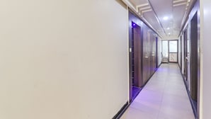A long, narrow hallway with a tiled floor and walls, leading to a door at the end. - Fabexpress Grand Inn (Lucknow)