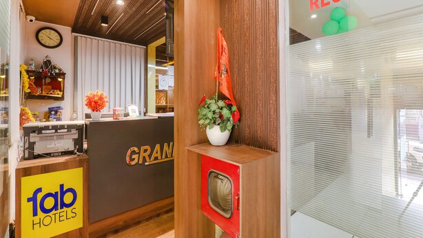 A reception area with a wooden counter, a clock, and a reception sign. - Fabexpress Grand Inn (Lucknow)