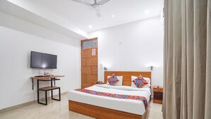A modern hotel room with a wooden bed, a flat-screen TV, a desk, and a wardrobe. - Fabhotel Prime Residency (New Delhi)