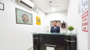A reception desk with a glass top, a framed artwork above it, and a sign for 'fab hotels' on the wall. - Fabhotel Prime Residency (New Delhi)