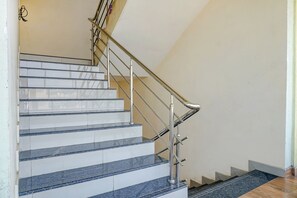 Una scala con gradini in marmo bianco e blu, corrimani in metallo e un pianerottolo rivestito di moquette.