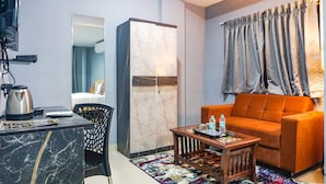 A modern living room with a sofa, a coffee table, a TV, and a wardrobe. - Fabhotel Grey Inn (Pune)