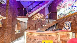 A reception area with a brick wall, a staircase, and a reception desk. - Fabhotel Nirvana Grand By Io (Amritsar)