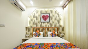 A hotel room with a bed, a headboard with a heart-shaped decoration, and a patterned bedspread. - Fabhotel Nirvana Grand By Io (Amritsar)
