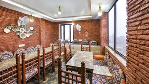A dining area with brick walls, patterned seating, and a view through a large window. - Fabhotel Nirvana Grand By Io (Amritsar)