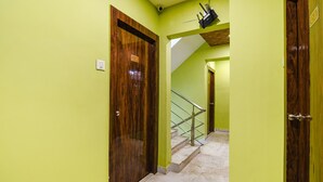A hallway with a wooden door labeled "C-3" and a staircase with a metal railing. - Fabhotel Divine Chariot (Barasat)