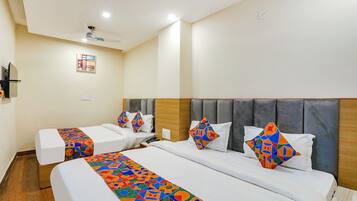 A hotel room with two beds, each with a colorful geometric-patterned bedspread and matching pillows.
