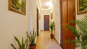 A hallway with a wooden door, potted plants, and framed pictures on the walls.