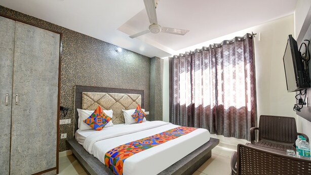 Una habitación de hotel con cama, armario, televisor y ventilador de techo.