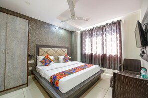 Una habitación de hotel con cama, armario, televisor y ventilador de techo.